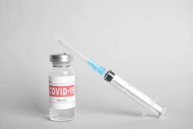 Photo of Vial with coronavirus vaccine and syringe on light background