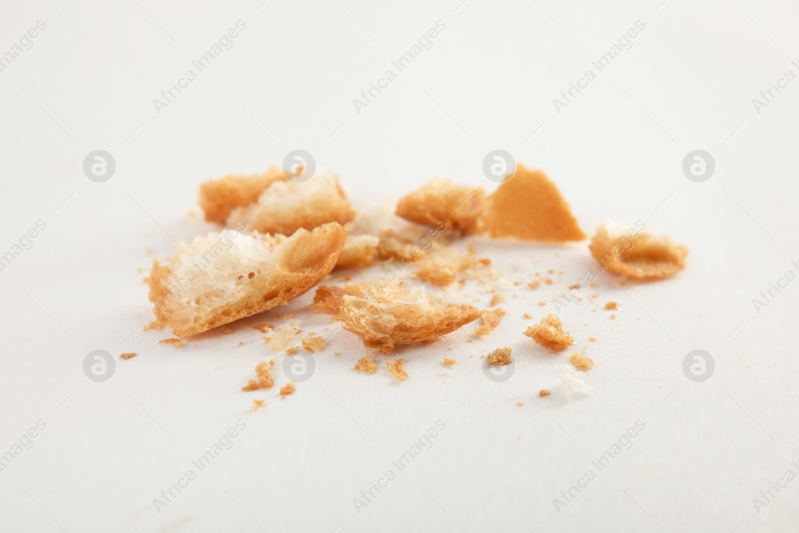 Photo of Scattered bread crumbs on white background, closeup