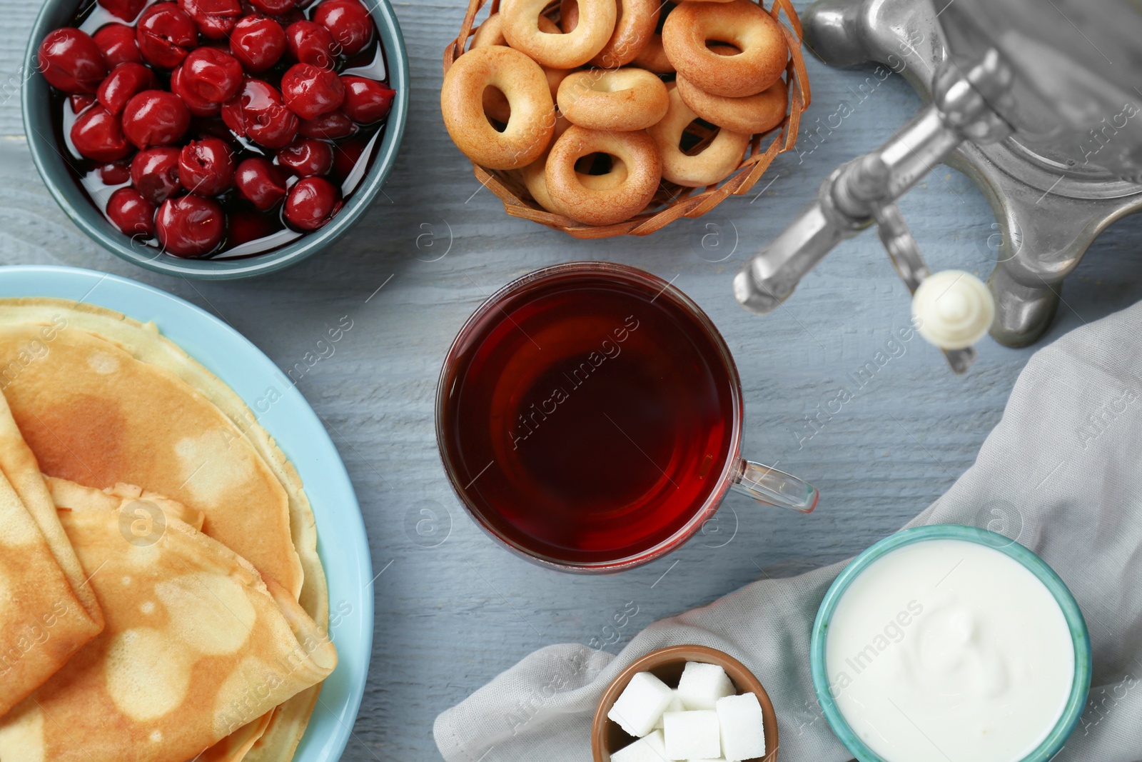 Photo of Flat lay composition with aromatic tea and treats on light blue wooden table