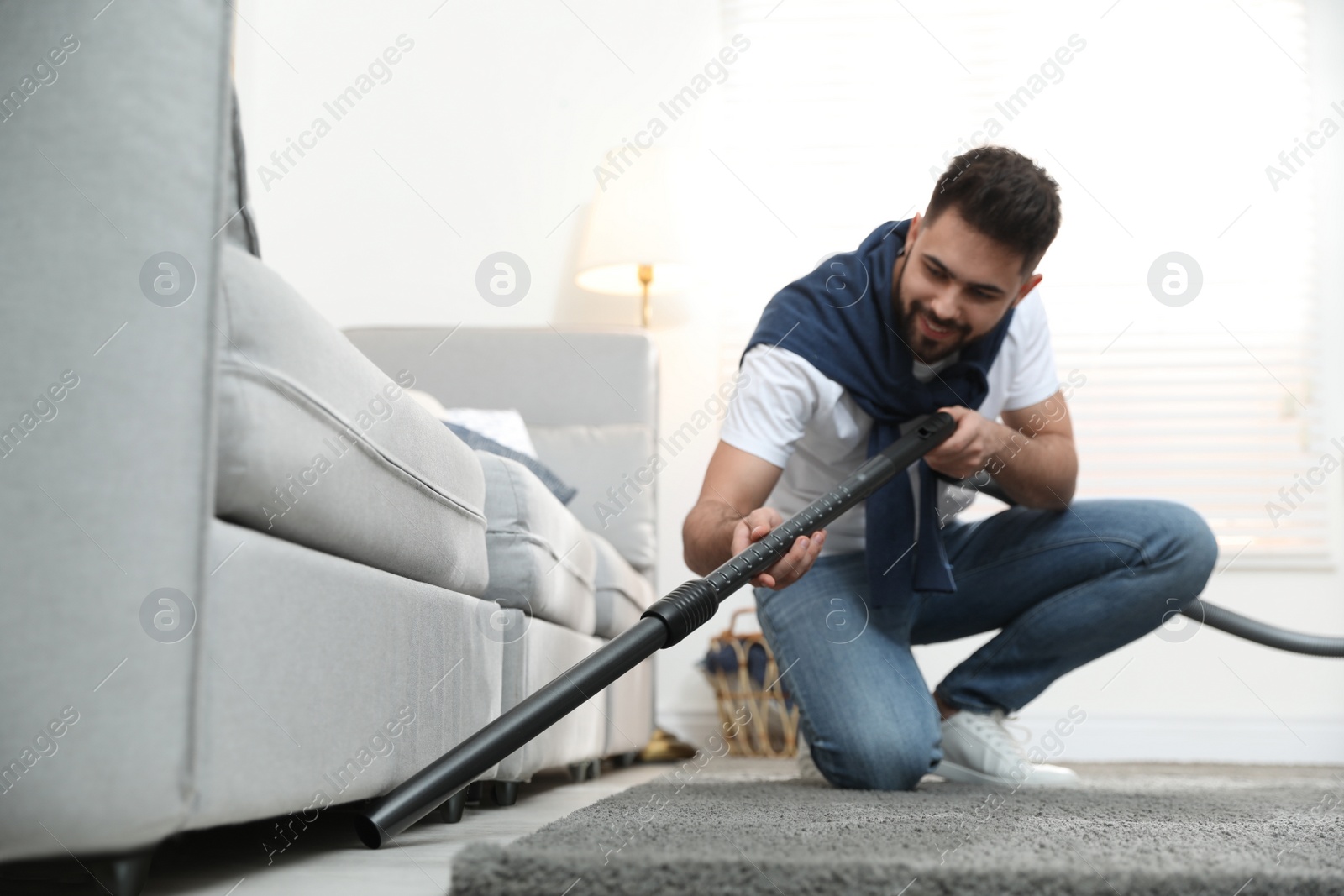 Photo of Young man using vacuum cleaner at home