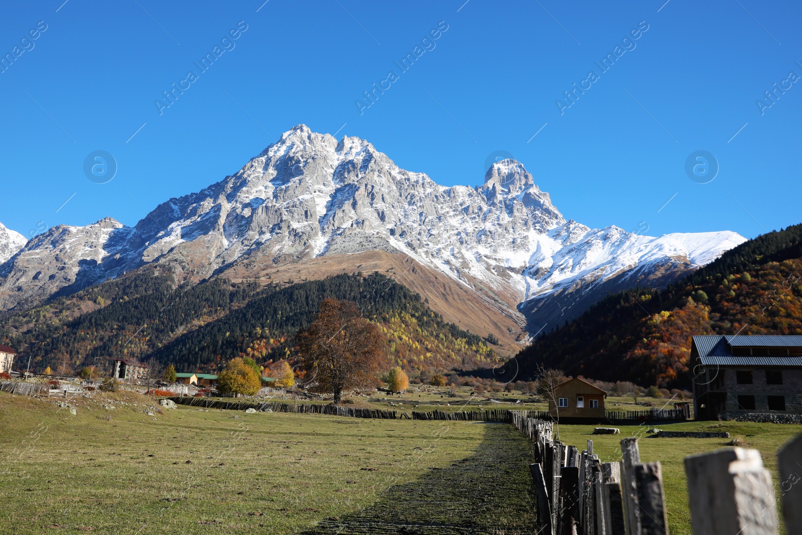 Photo of Picturesque view of village in high mountains under blue sky on sunny day