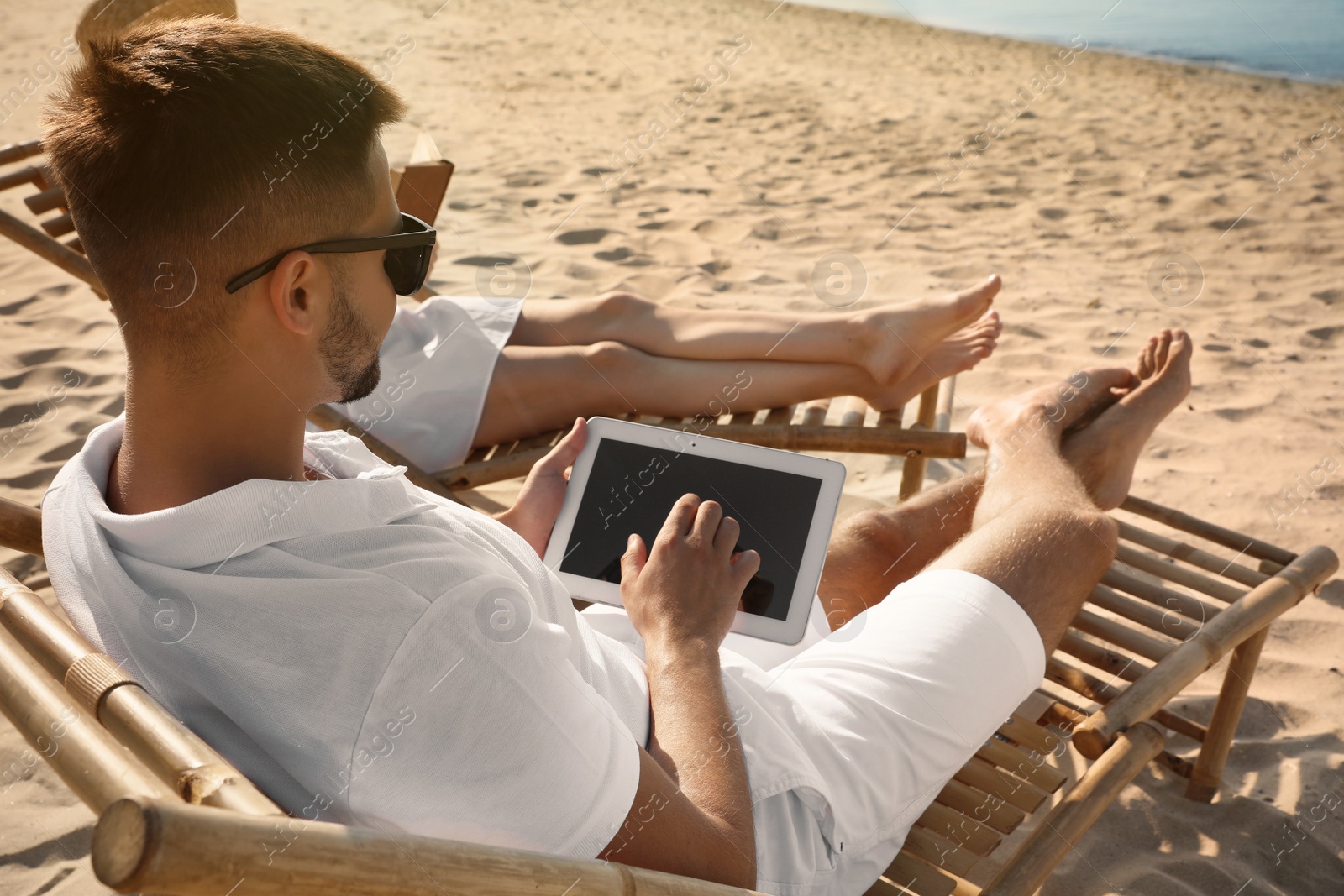 Photo of Young couple relaxing in deck chairs on sandy beach