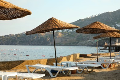 Many lounge chairs and beach umbrellas on sea shore