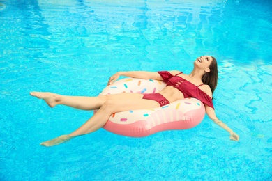 Photo of Beautiful young woman on inflatable ring in swimming pool