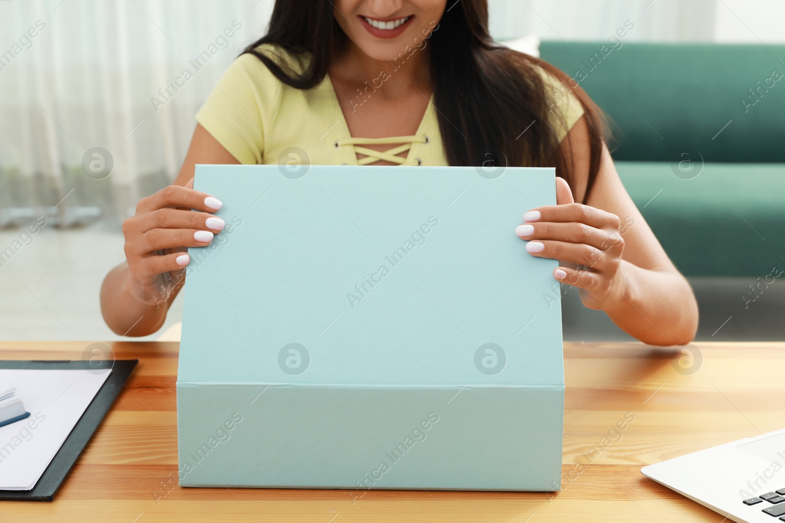 Photo of Happy young woman opening parcel at home, closeup. Internet shopping