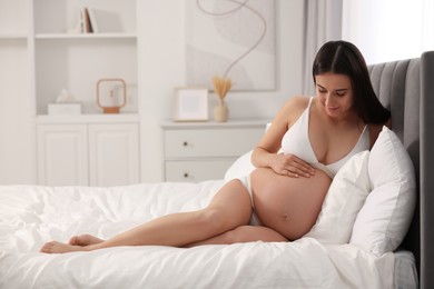 Photo of Beautiful pregnant woman in stylish comfortable underwear on bed at home