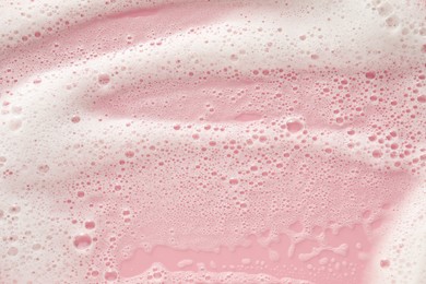 White washing foam on pale pink background, top view