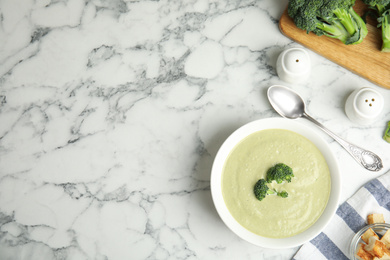 Photo of Delicious broccoli cream soup served on white marble table, flat lay. Space for text