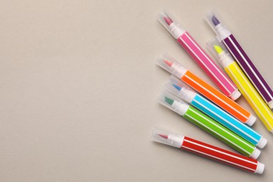 Photo of Many bright markers on light grey background, flat lay. Space for text