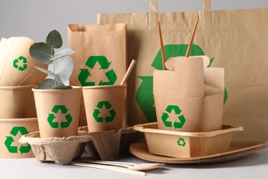 Image of Set of eco friendly food packaging with recycling symbols on light background