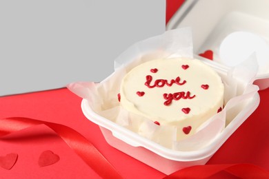 Tasty bento cake with Love You inscription in takeaway packaging on red table, closeup. Space for text