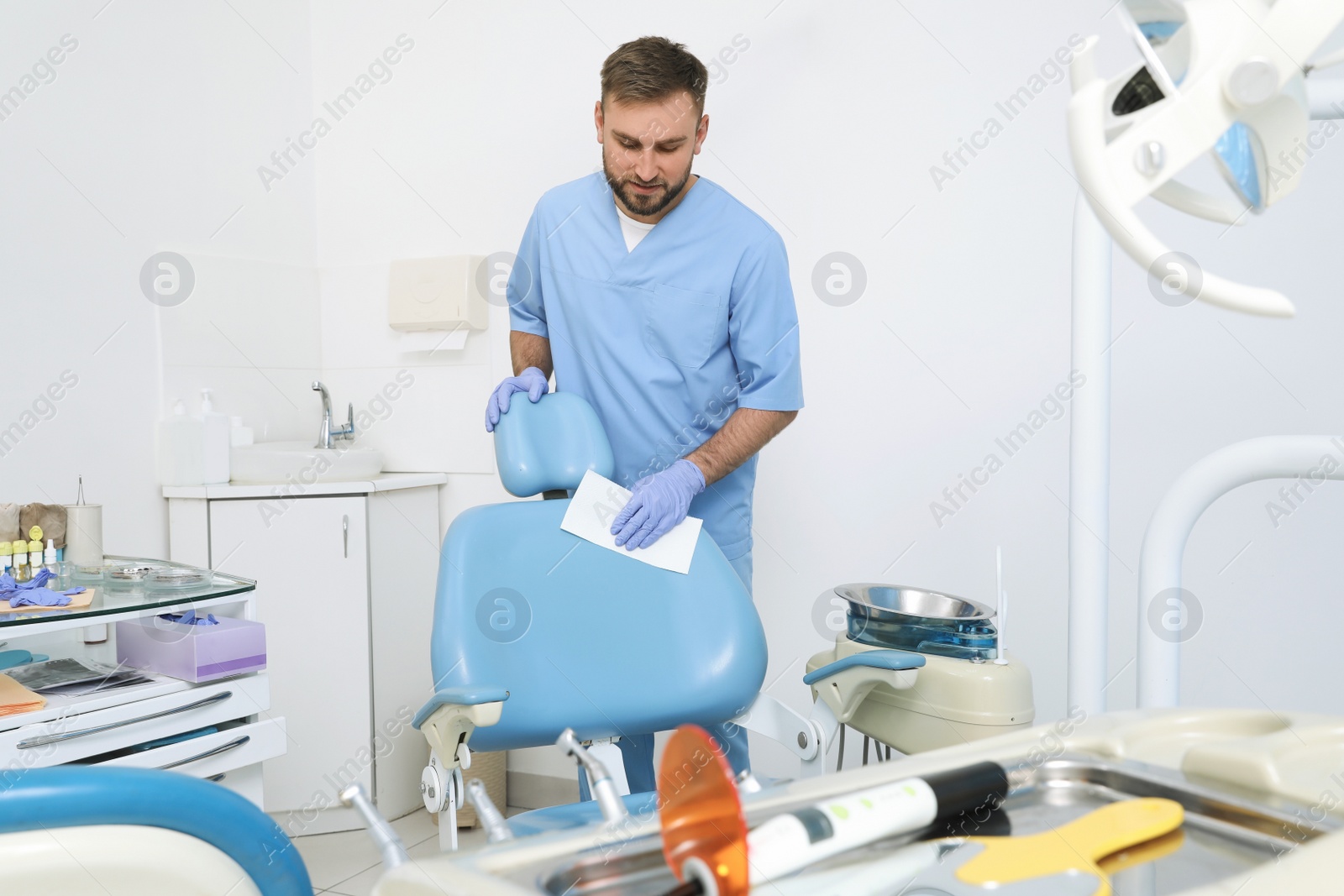 Photo of Professional dentist in uniform cleaning workplace  indoors