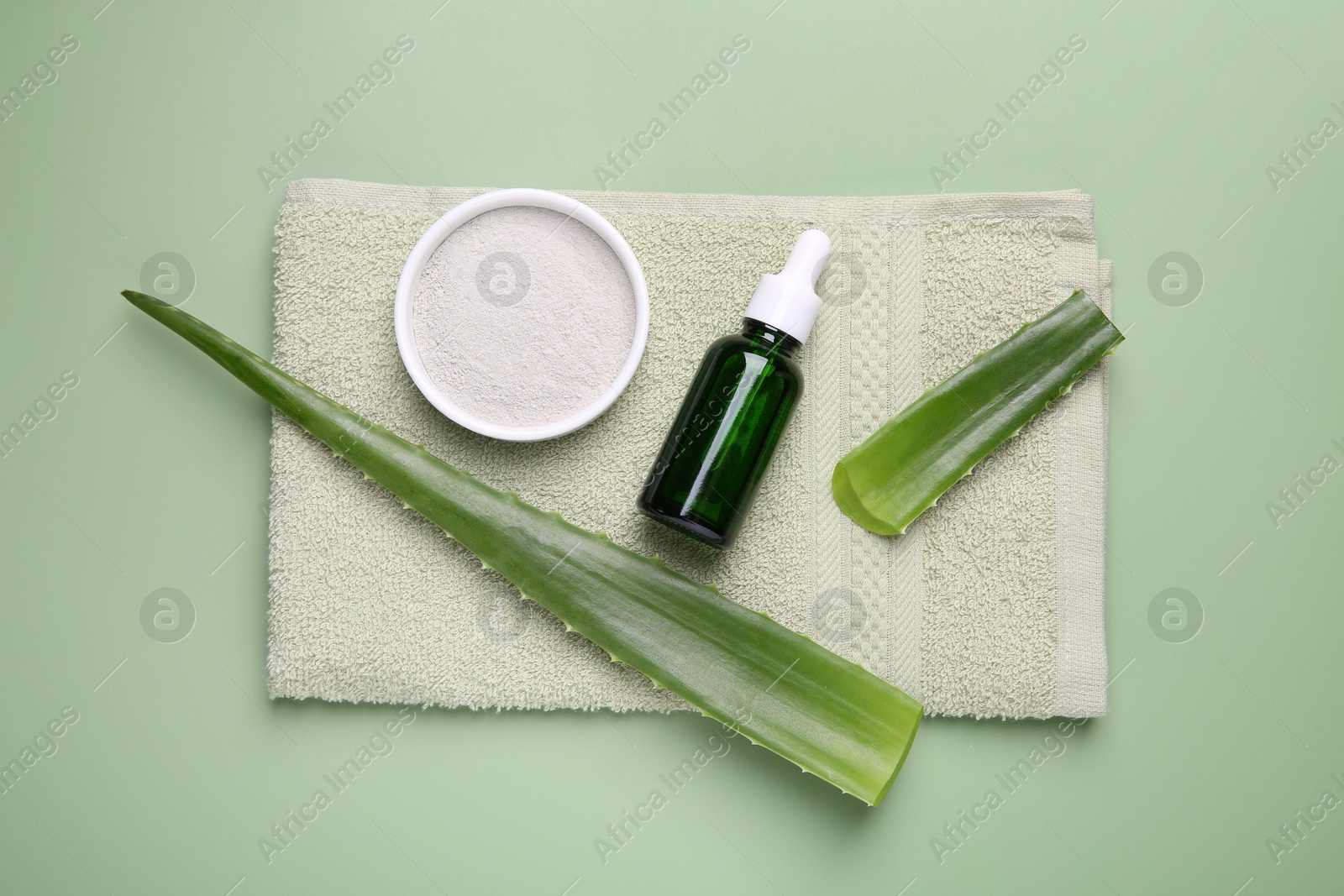 Photo of Cosmetic products, aloe leaves and towel on pale green background, top view