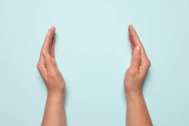 Photo of Woman holding on light blue background, closeup of hands. Space for text