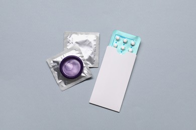 Photo of Contraception choice. Pills and condoms on grey background, flat lay