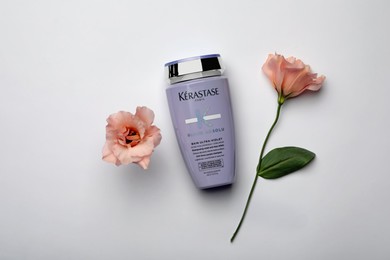 Photo of MYKOLAIV, UKRAINE - SEPTEMBER 07, 2021: Kerastase shampoo and beautiful flowers on light grey background, flat lay