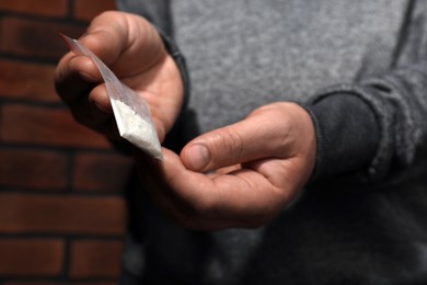 Drug addiction. Man with plastic bag of cocaine on blurred background, selective focus