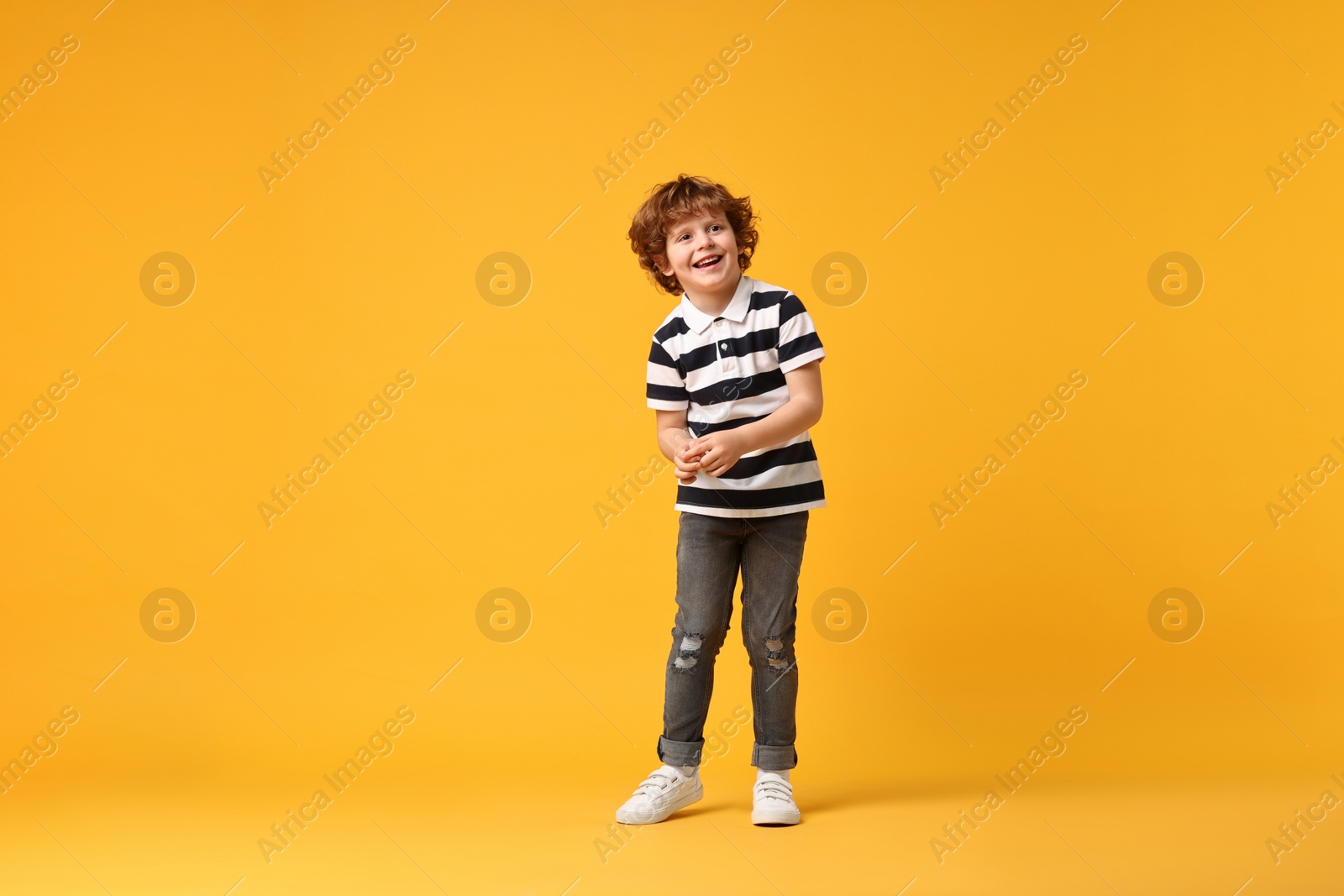 Photo of Happy little boy dancing on yellow background