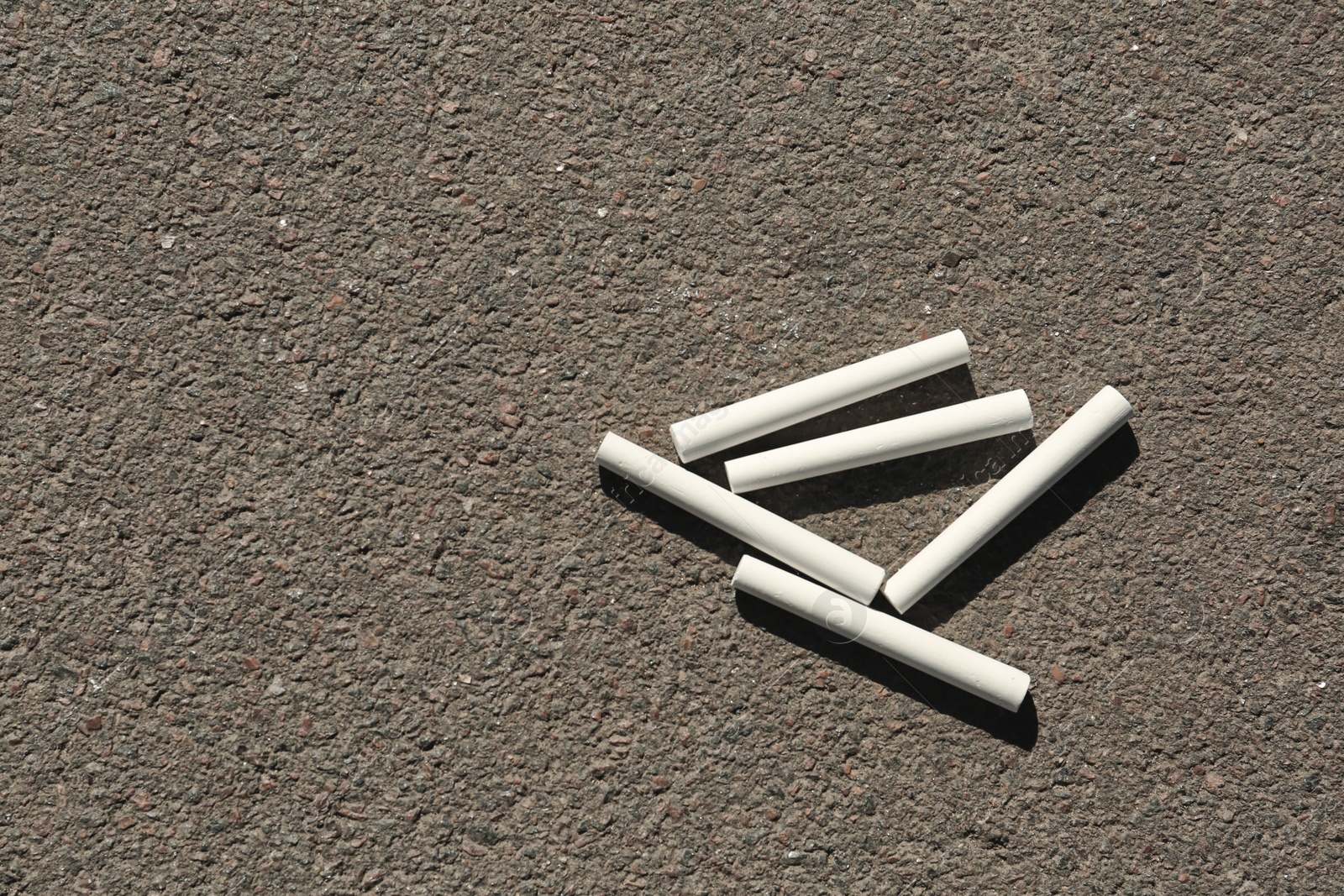 Photo of White chalk sticks on asphalt, top view