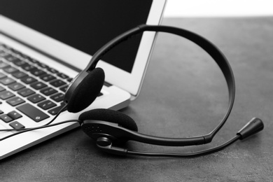 Photo of Modern laptop and headset on table. Technical support concept