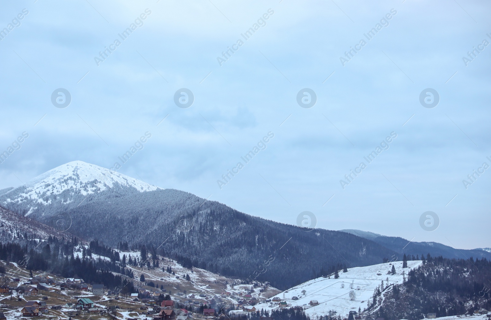 Photo of Winter landscape with mountain village near conifer forest