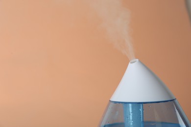Modern air humidifier on orange background, closeup. Space for text