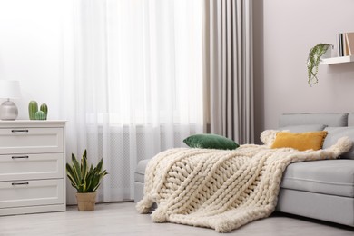 Living room interior with knitted merino wool blanket on sofa