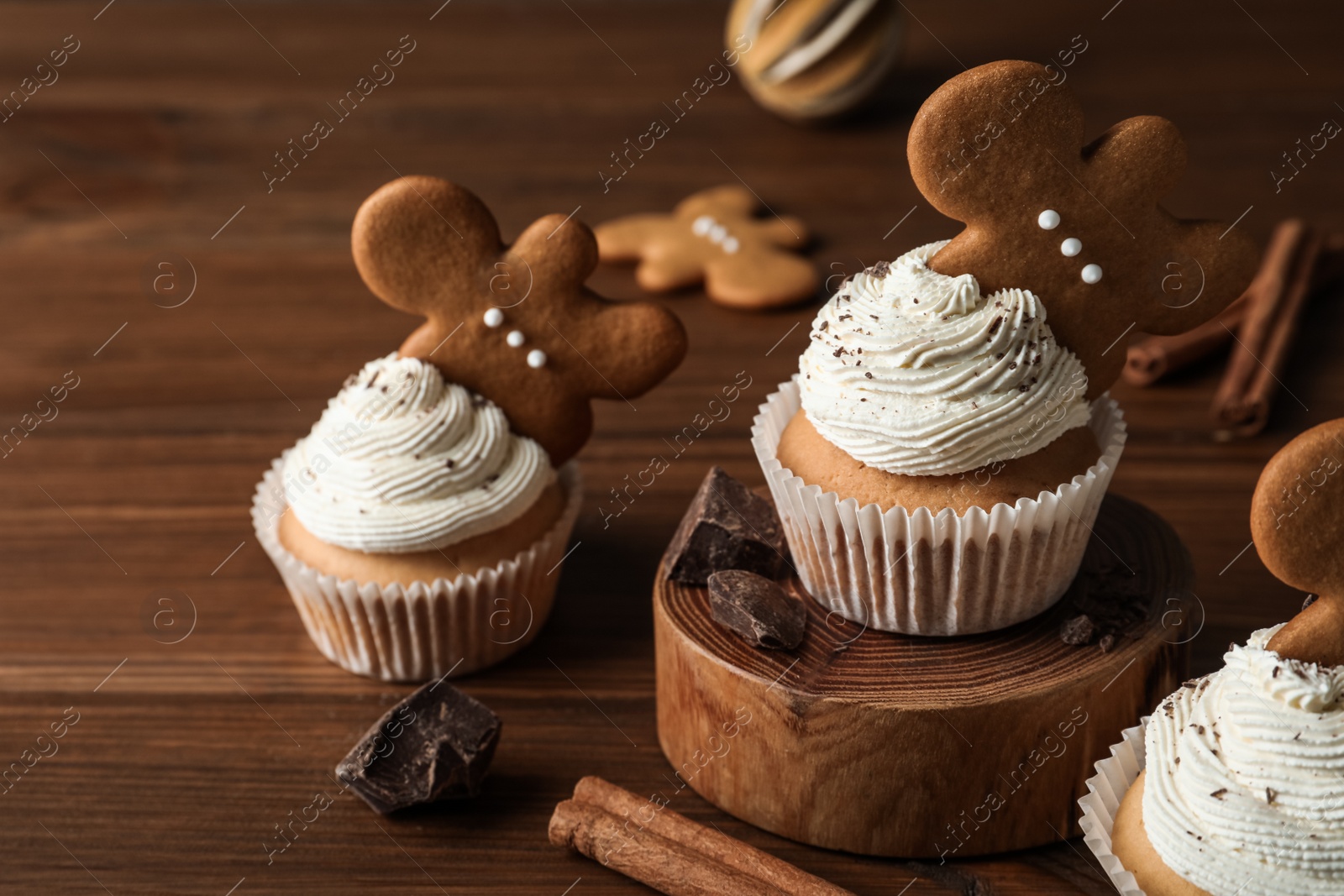 Photo of Tasty Christmas cupcakes with gingerbread man cookies on wooden table