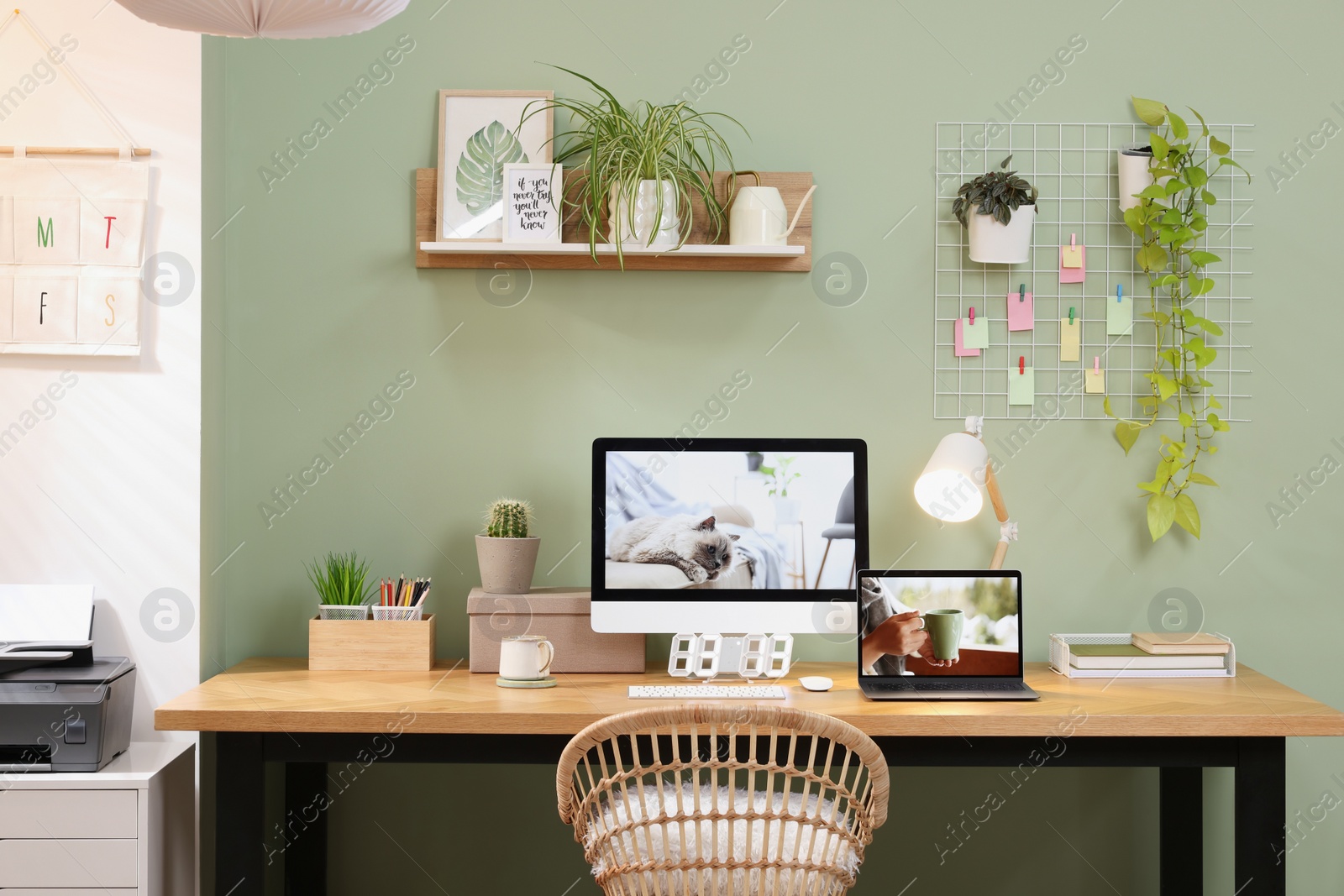 Photo of Stylish workplace with computer, laptop and lamp near olive wall at home