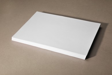 Photo of Stack of blank paper sheets on light brown background, space for text