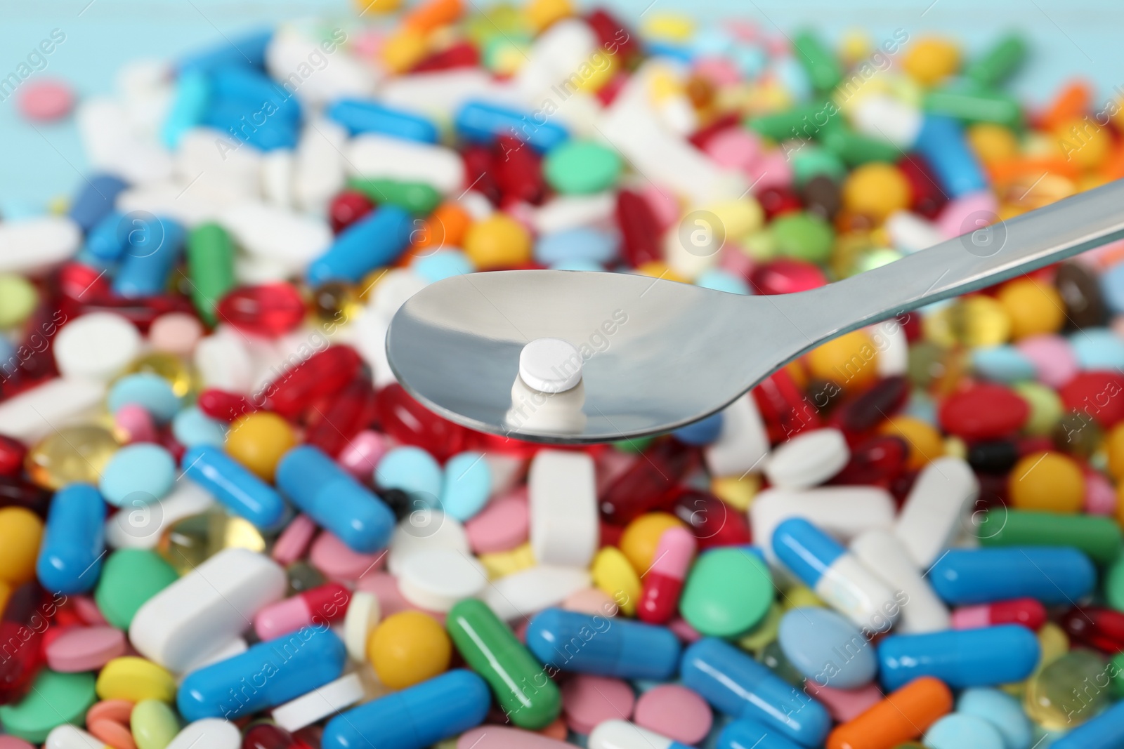 Photo of Spoon with weight loss pill over table, closeup