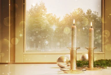 Burning candles, Christmas balls and  fir tree branch on white window sill indoors 