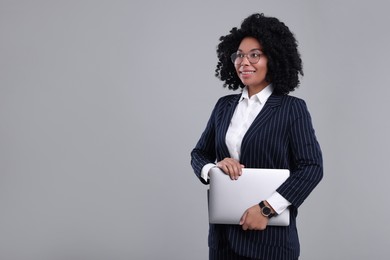 Young businesswoman with laptop on grey background. Space for text