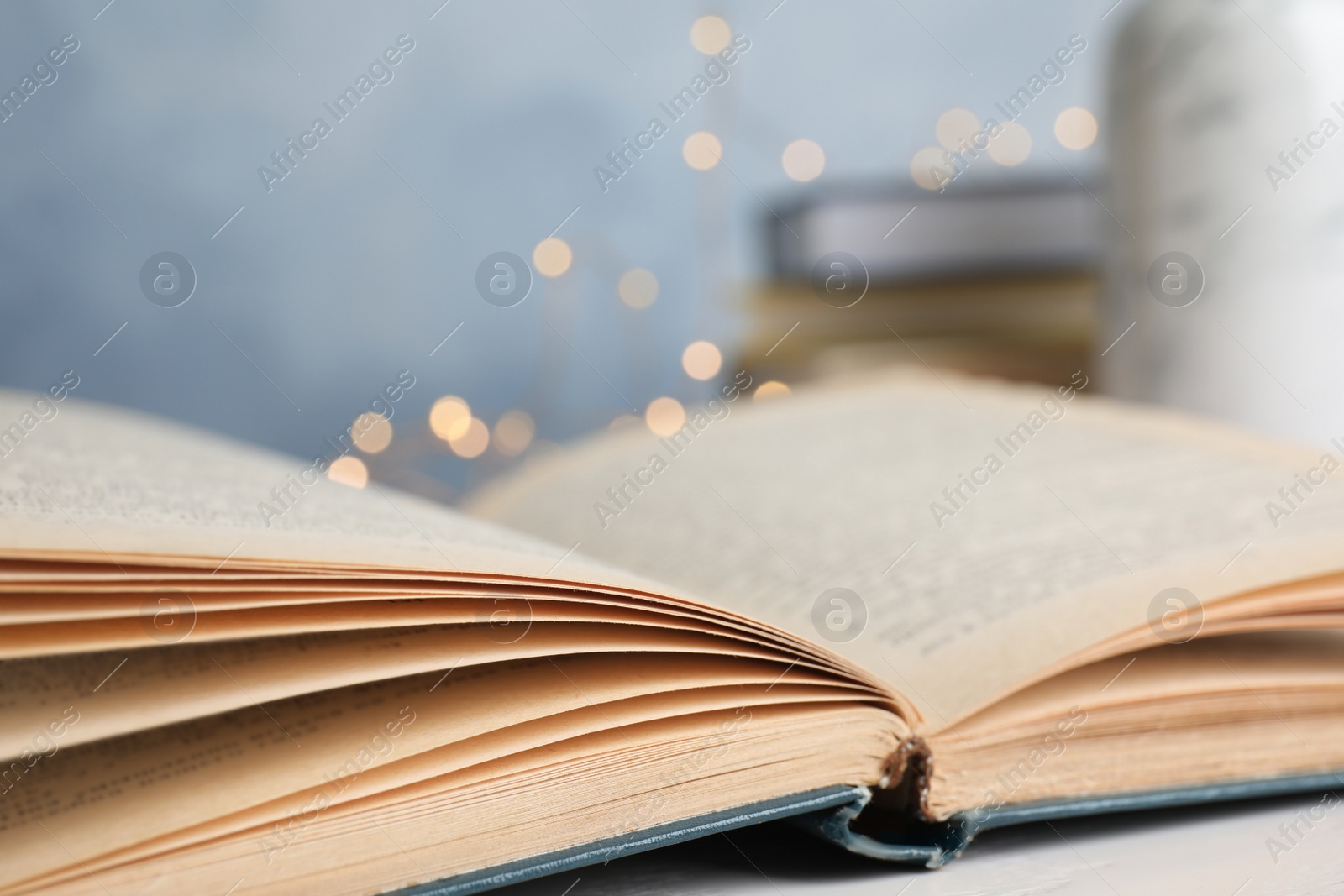 Photo of Open hardcover book on table against blurred background, closeup