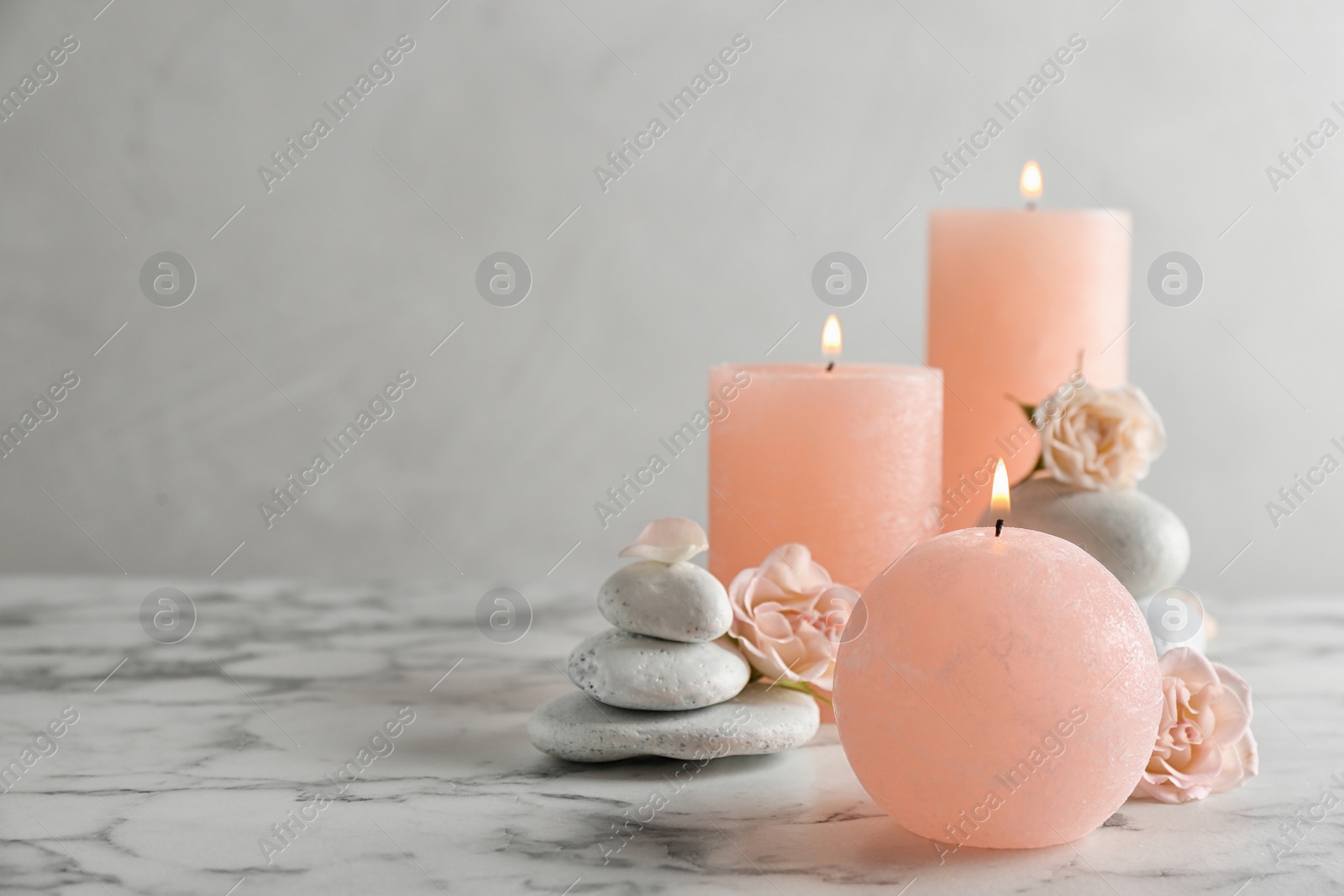 Photo of Burning candles, spa stones and flowers on table. Space for text