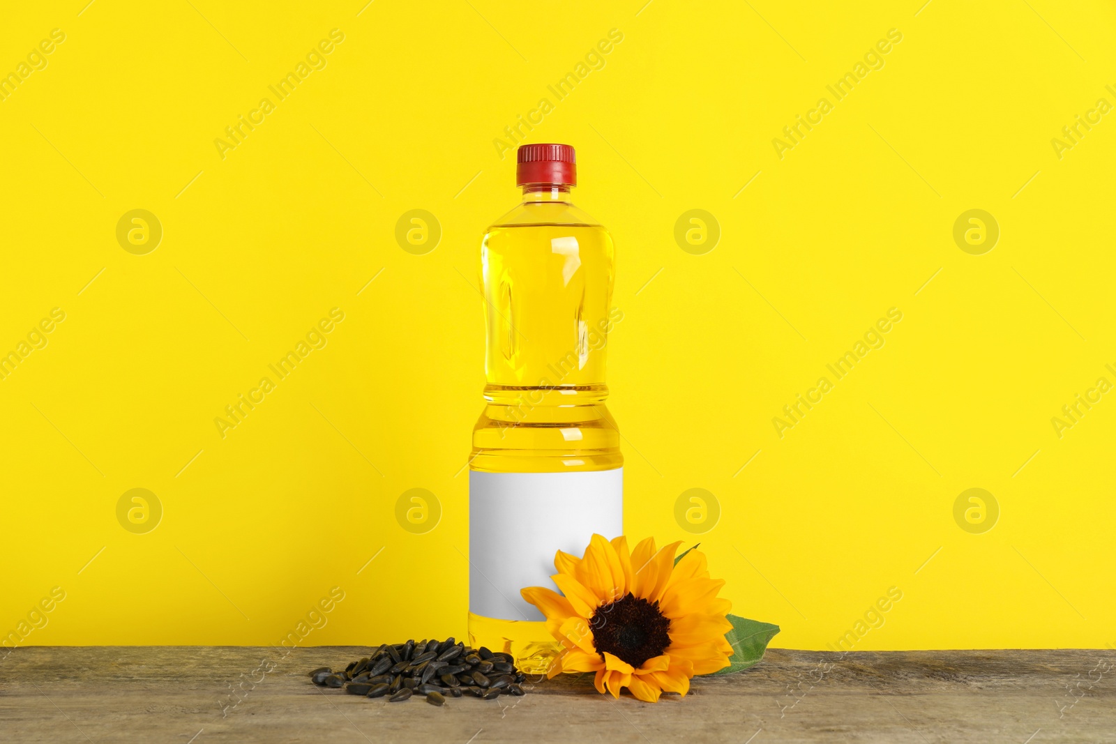 Photo of Bottle of cooking oil, sunflower and seeds on wooden table