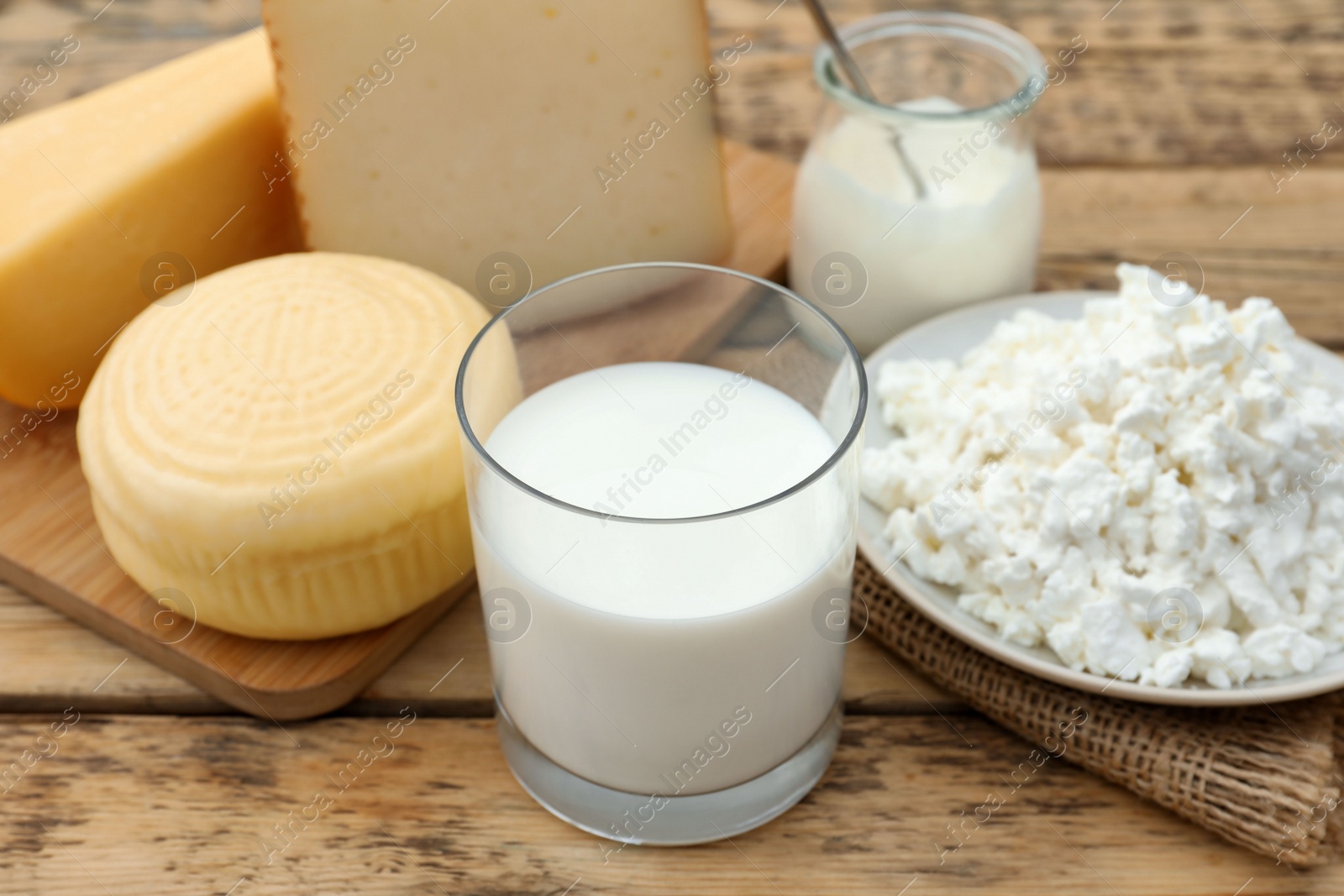 Photo of Tasty cottage cheese and other fresh dairy products on wooden table