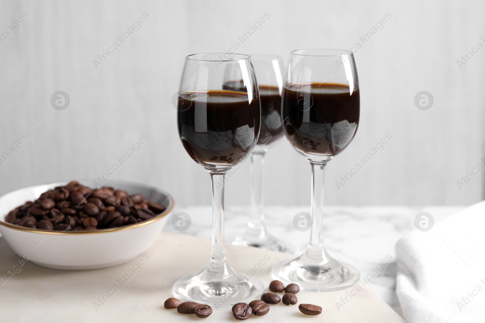 Photo of Glasses of coffee liqueur and beans on white table