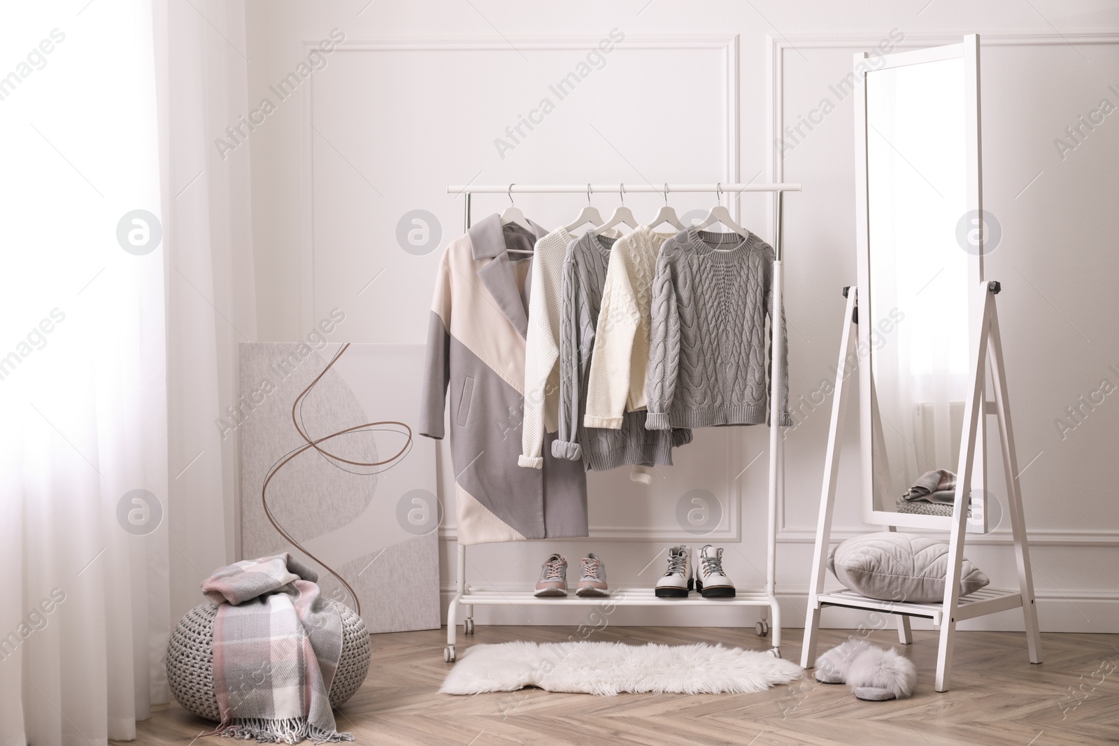 Photo of Rack with stylish warm clothes and mirror in dressing room