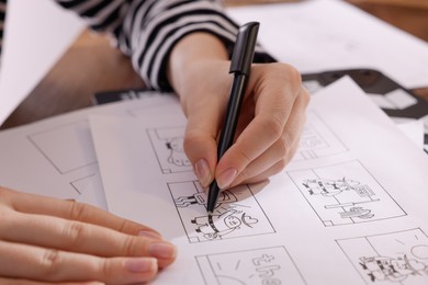 Photo of Woman drawing cartoon sketch at workplace, closeup. Pre-production process