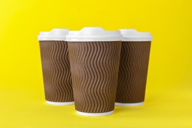 Paper cups with white lids on yellow background. Coffee to go
