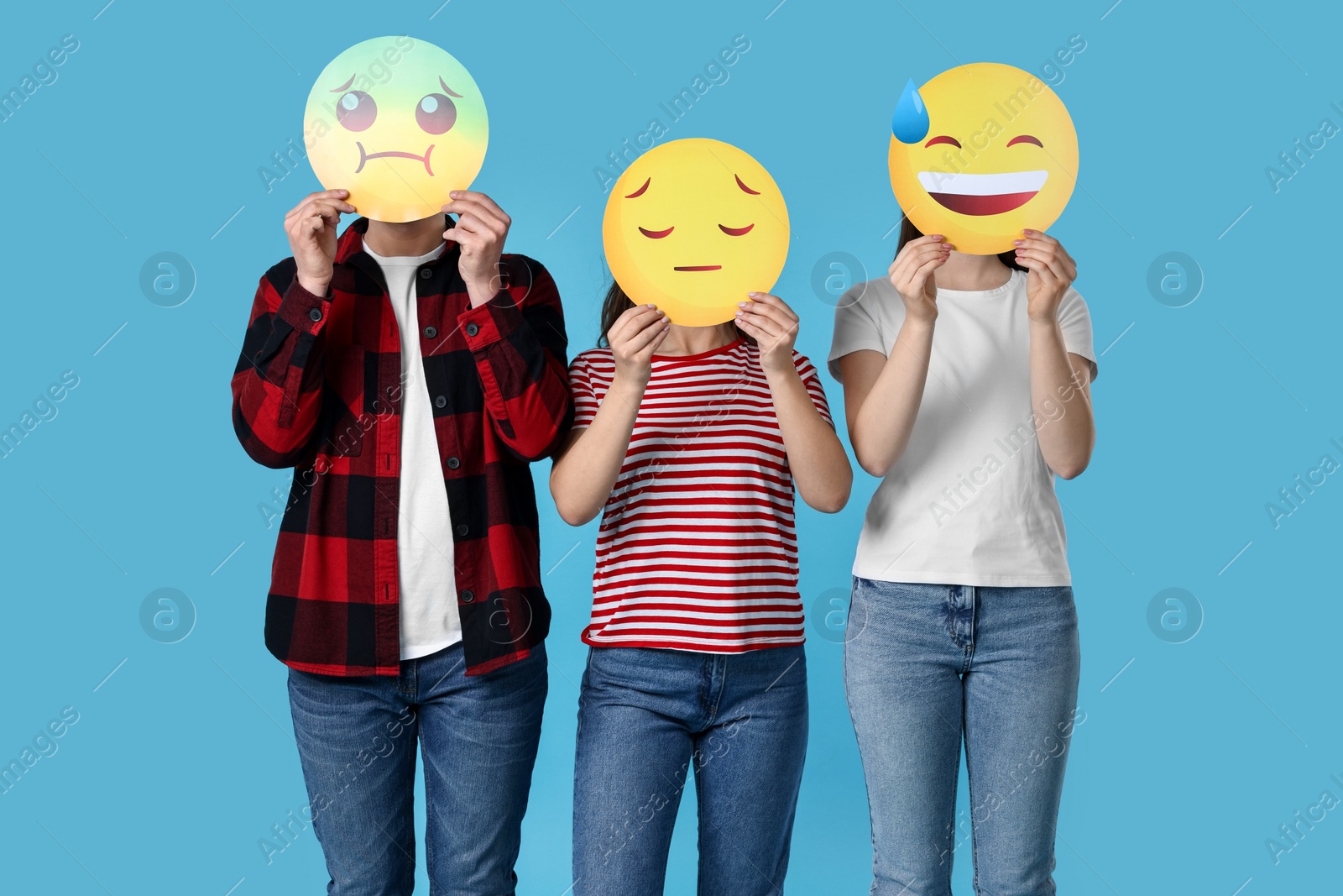 Photo of People covering faces with emoticons on light blue background