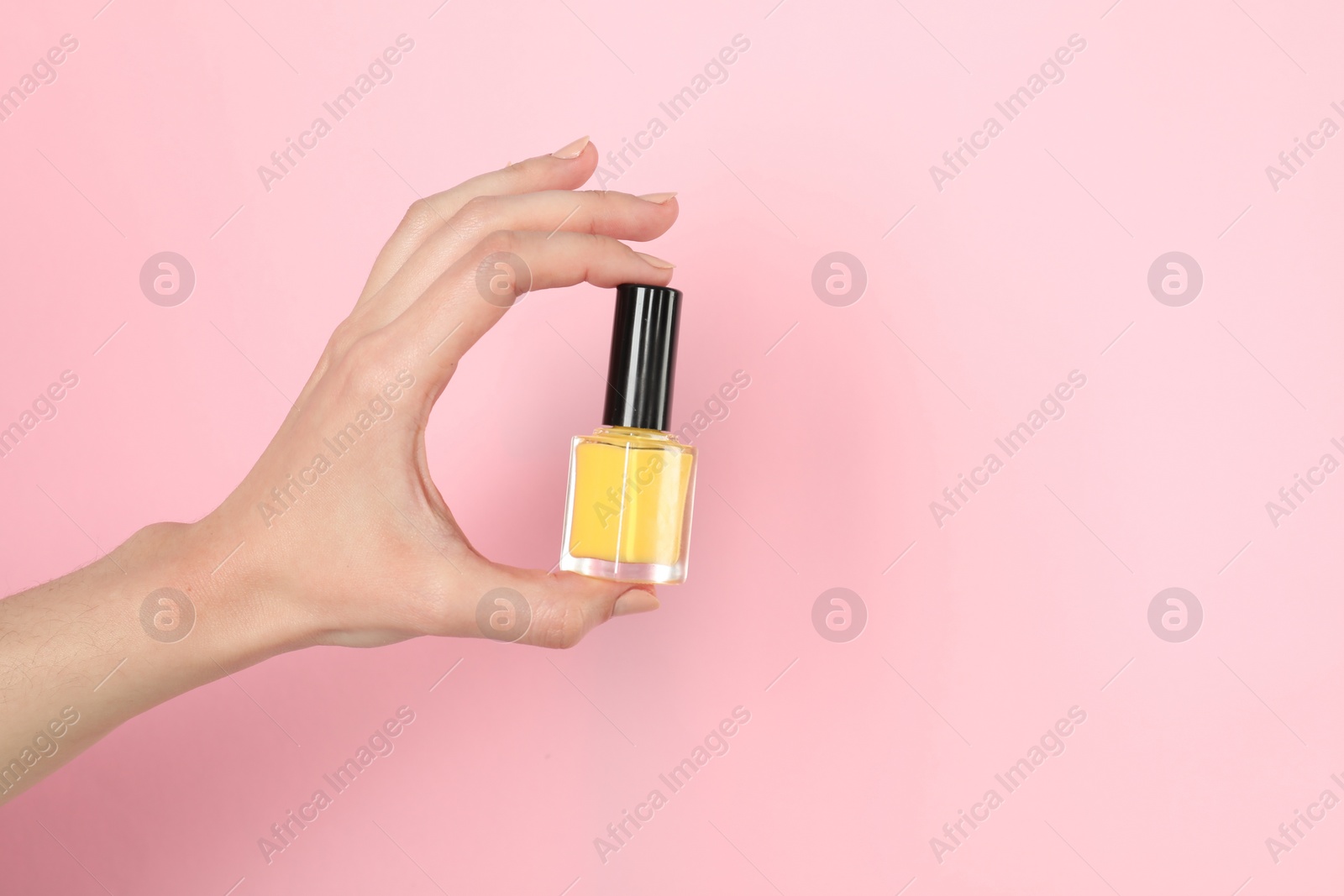 Photo of Woman holding nail polish on pink background, closeup. Space for text