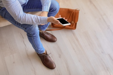 Photo of Man in elegant shoes using mobile phone indoors