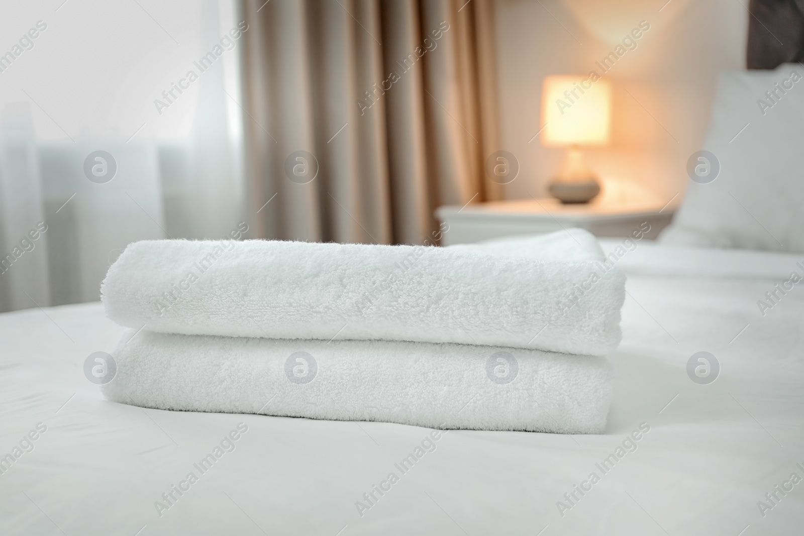 Photo of Stack of towels on bed in modern hotel room