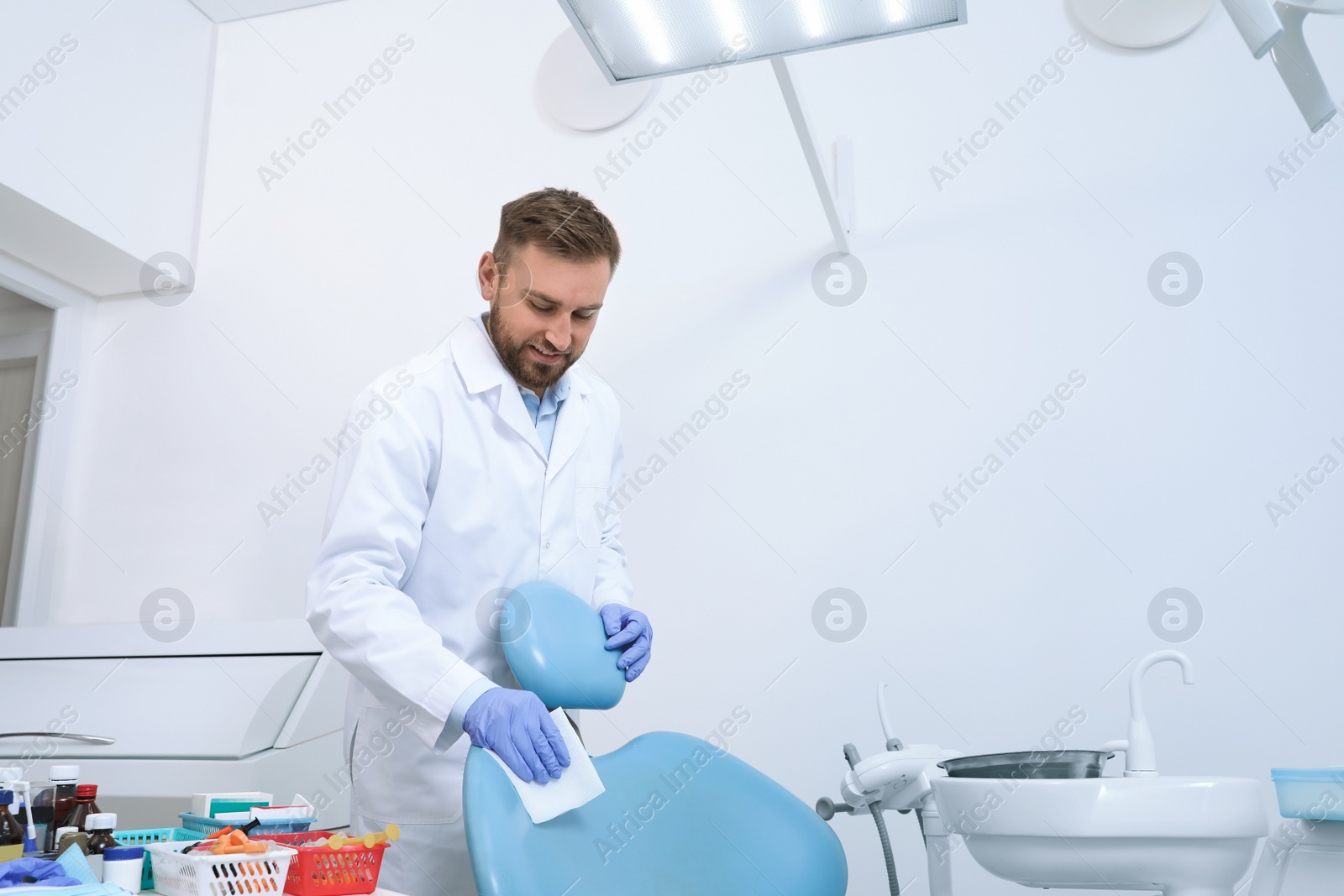 Photo of Professional dentist in white coat cleaning workplace  indoors