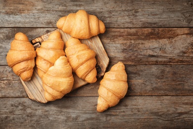 Photo of Tasty croissants on wooden background, top view