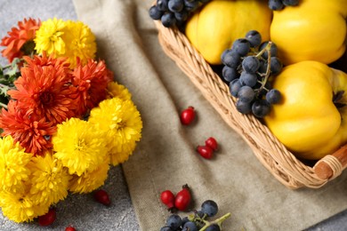 Photo of Beautiful chrysanthemum flowers, rose hip berries and sweet fruits on grey table, above view