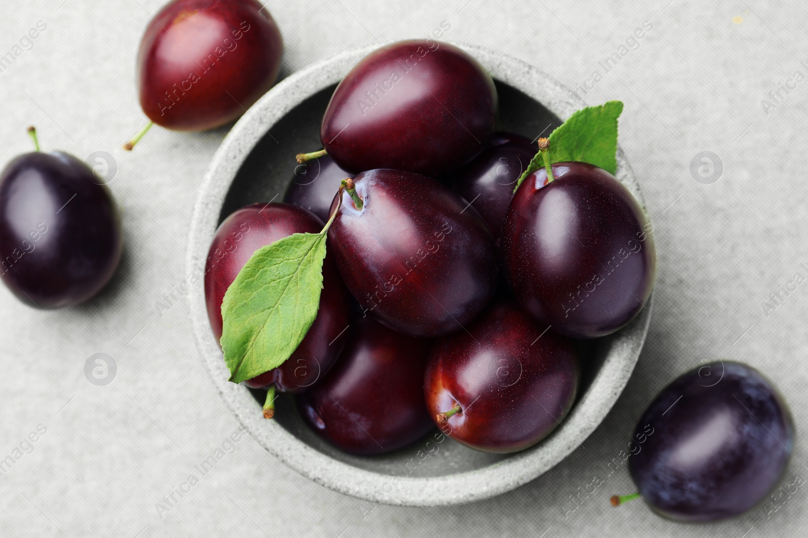 Photo of Tasty ripe plums on light fabric, flat lay