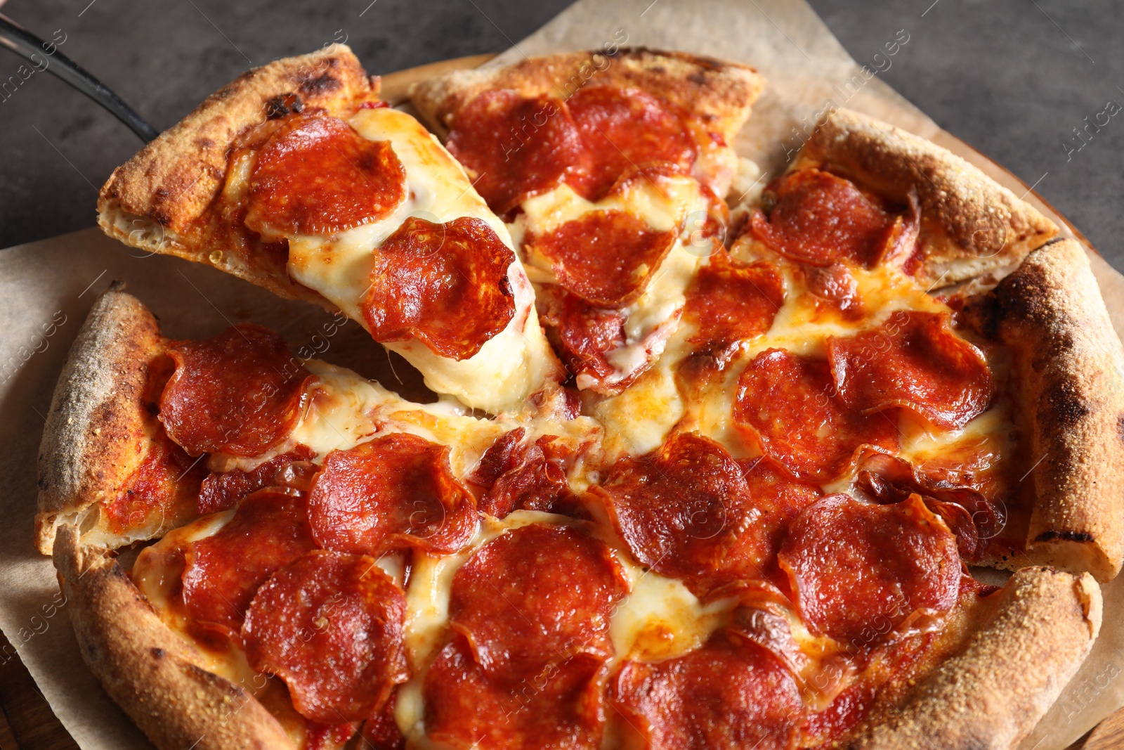 Photo of Taking piece of tasty pepperoni pizza at grey table, closeup